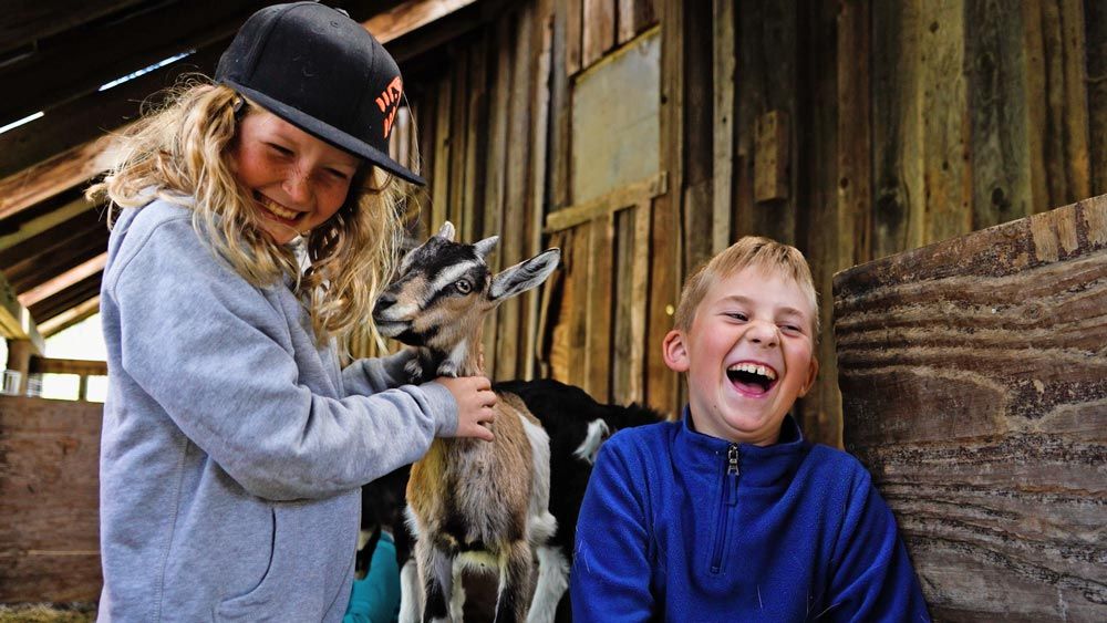 Nature Day Camp children laughing with baby goat