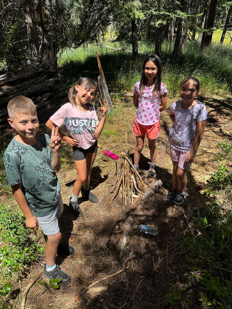 Nature Day Campers work as a team building a log cabin style campfire