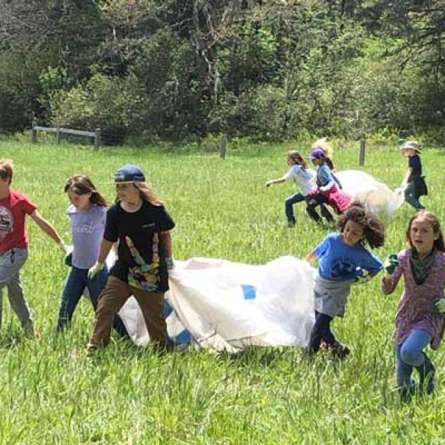 outdoor school students carrying tarps across meadow