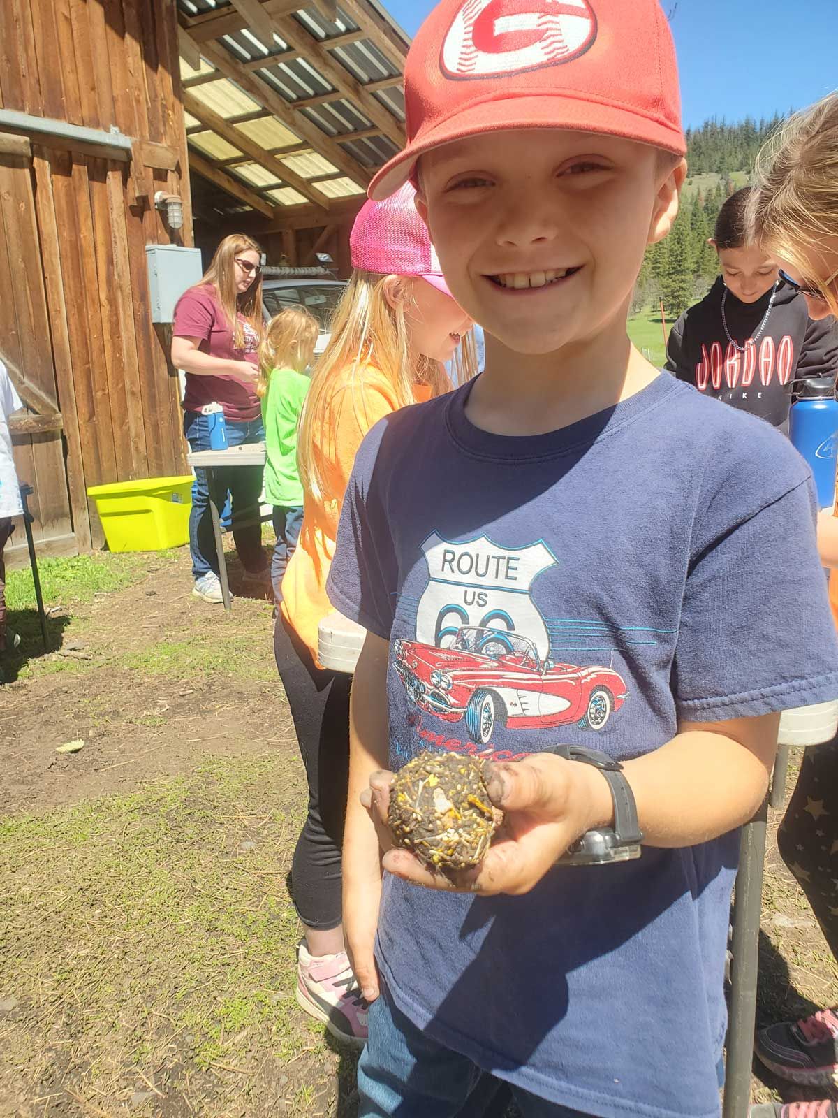 field trip student holding seed ball he made during farm tour project