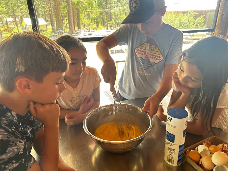 Nature Day Camp students in cookhouse whisking fresh eggs