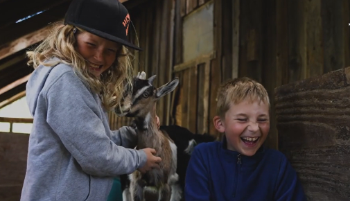 Children laugh and play with goats at Willow-Witt Ranch. 