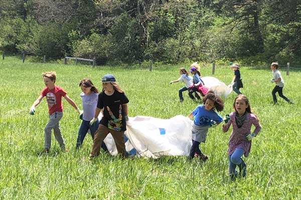 outdoor school students carrying tarps across meadow