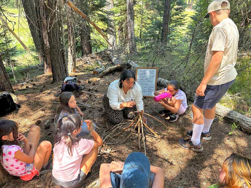 Outdoor School students watching staff demonstrate fire building techniques