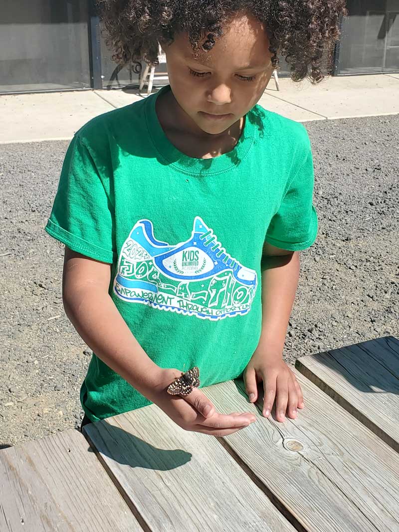 student with butterfly resting on her hand