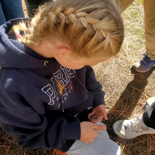 student looking at butterfly resting on her