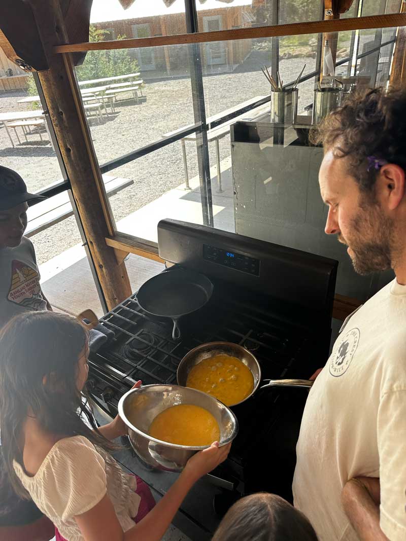 students cooking fresh scrambled eggs in cookhouse