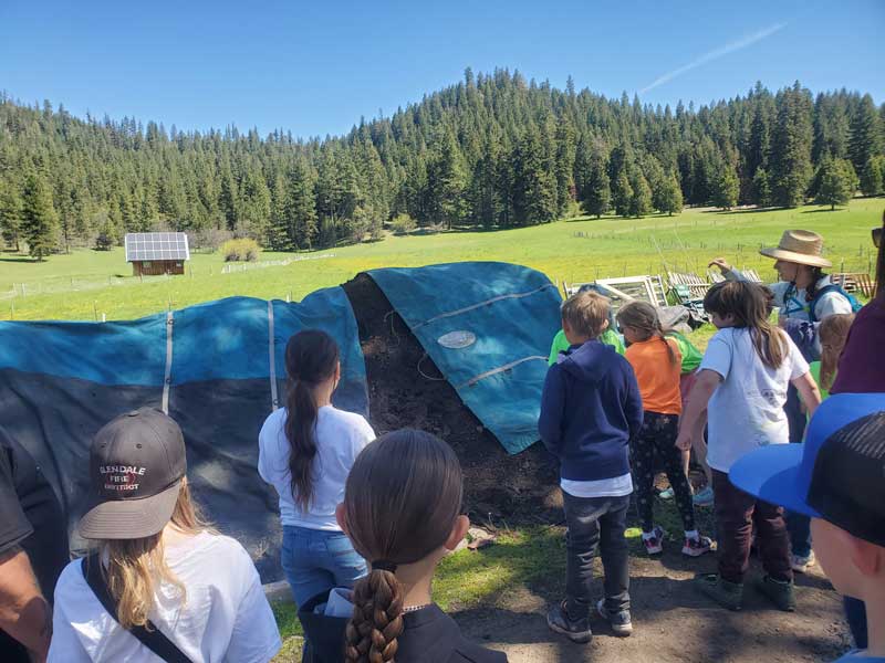 students gather around teacher at tarp-covered area