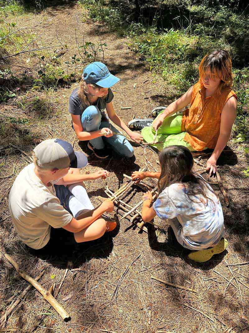 four students practicing fire building techniques
