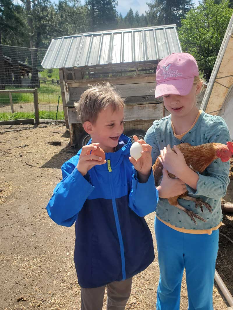 two students proudly hold a chicken and two eggs